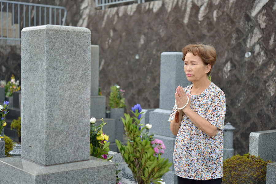 elderly woman with beads at gravesite